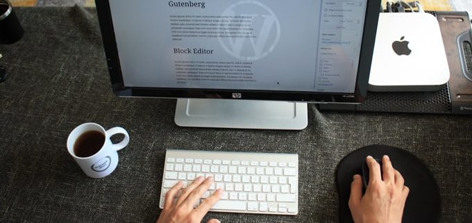vue de mains sur un clavier et une souris devant un écran d'une personne en train de planifier ses publications WordPress